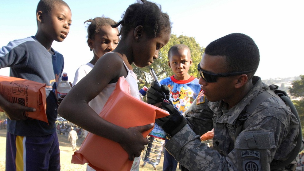 Spc. Juan Valencia marks the fingernail of a small girl to indicate she has gone through the distribution line in Port-au-Prince, Jan. 18, 2010