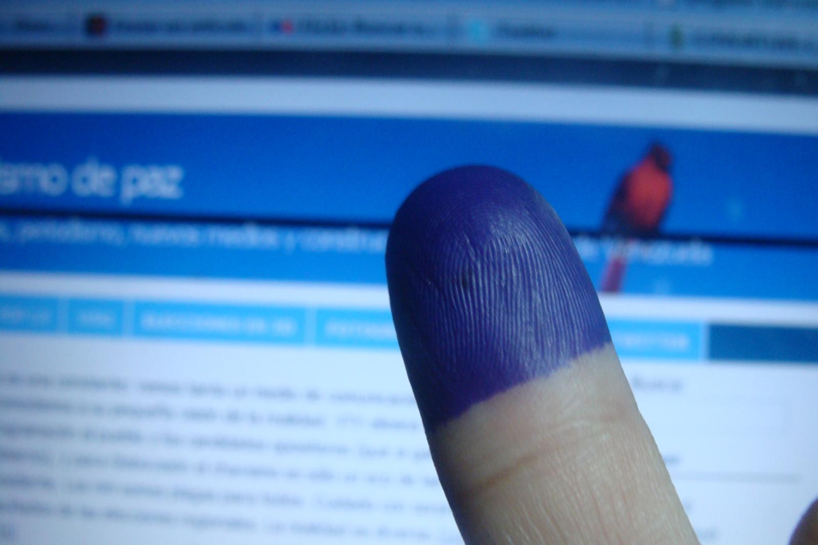 A voter holds up a dye-dipped finger, a symbol of voting in an election. Photo courtesy of Luis Carlos Díaz via Flickr.